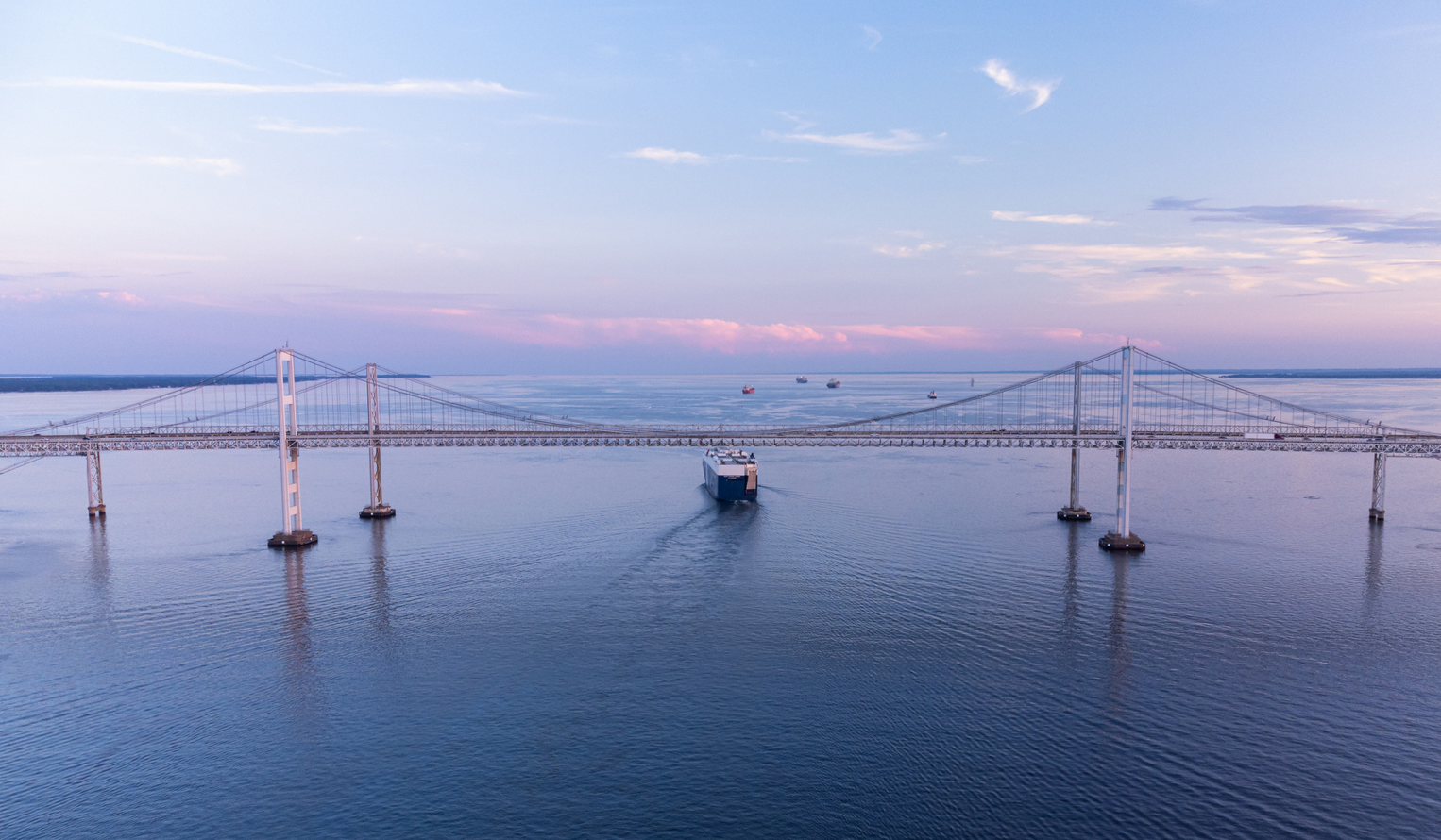 Boats and barge passing by the Chesapeake Bay bridge in Maryland