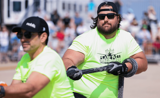 Two members of the Noblis team are shown pulling a rope for the Dulles plane pull.