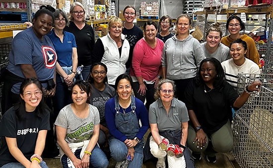 Group of Noblis volunteers pose for a photo in the Food for Others distribution warehouse.