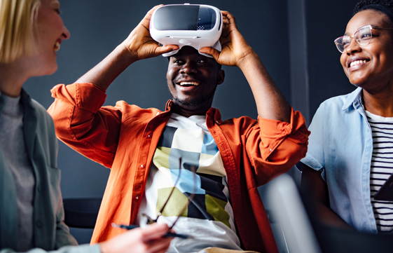 several people smiling while one man takes off a VR headset
