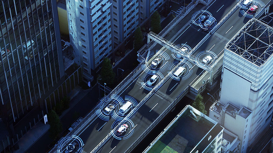 Aerial view of a smart highway with autonomous cars, highlighted by blue sensor waves
