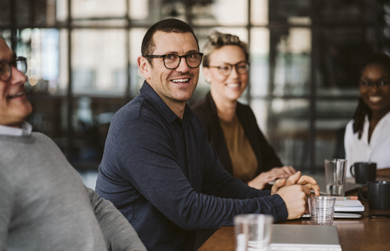 four people sit talking and smiling together in an office setting