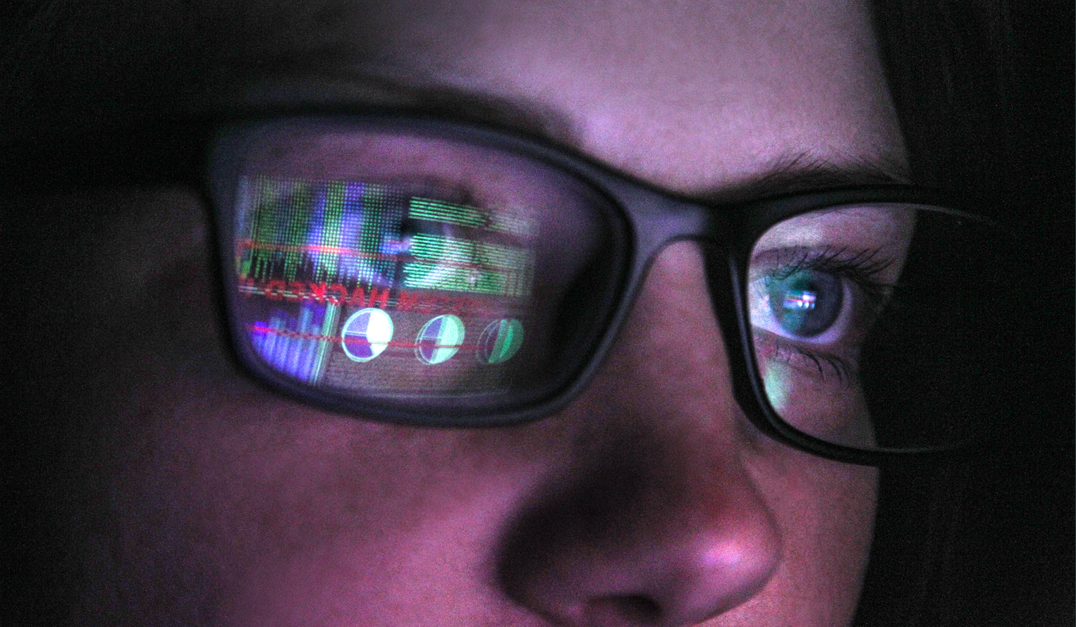 close up on face of a woman wearing glasses with computer screen reflected, data dashboards