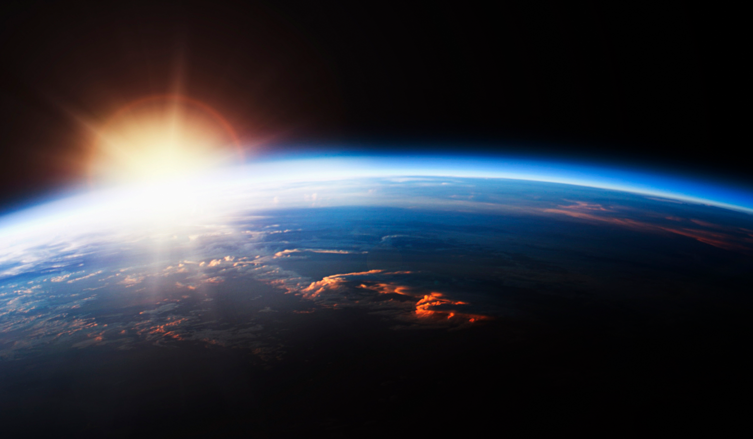 sun coming up over the horizon of the earth seen from space