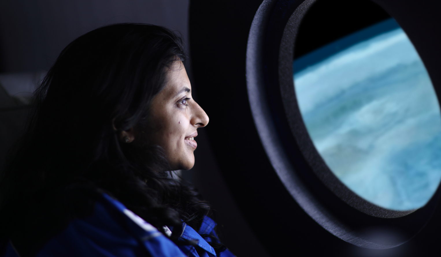 a woman looks out the window of a spacecraft at the earth's atmosphere