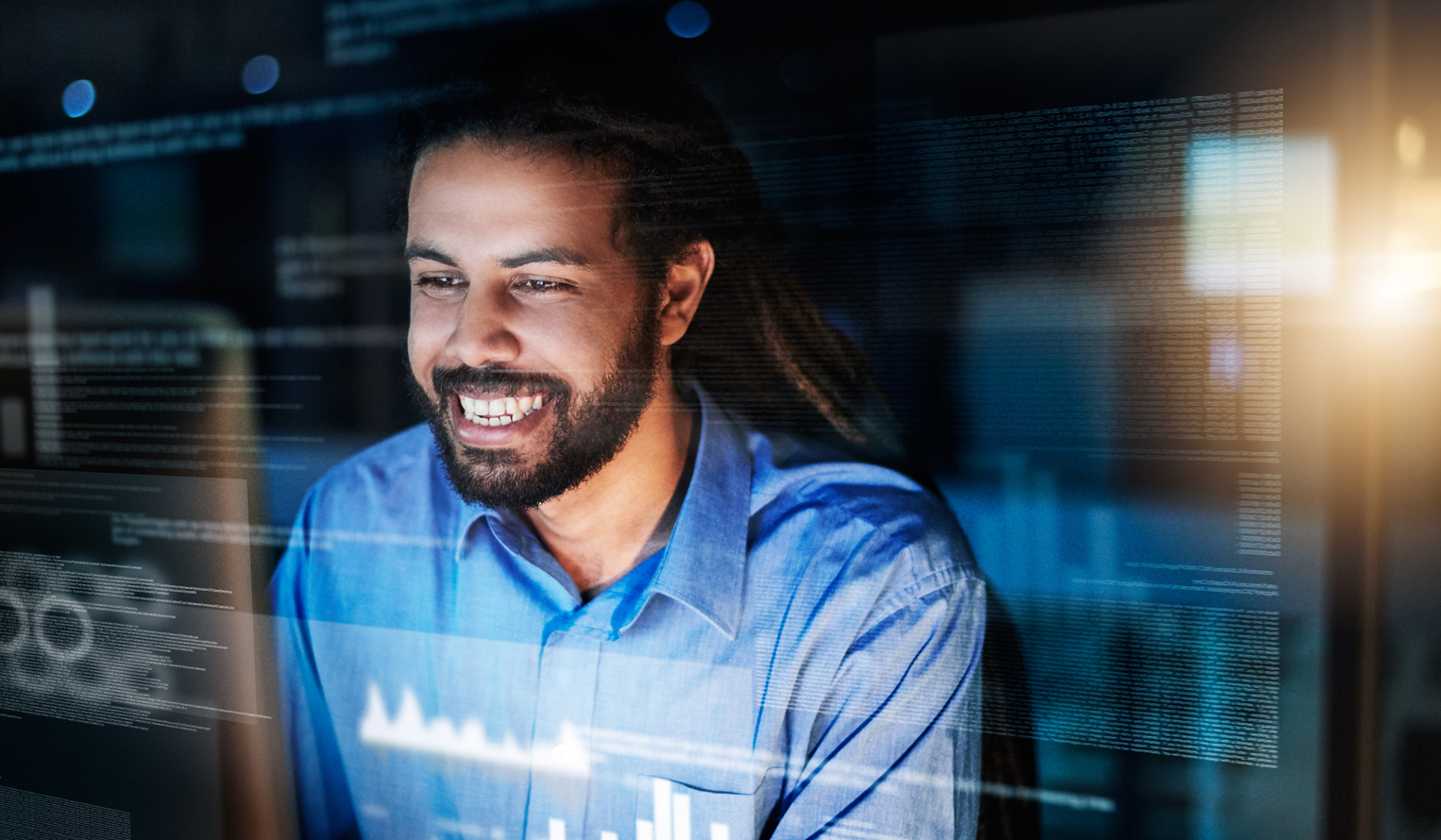 a Black male smiles at his computer screen, images of data float in front of him