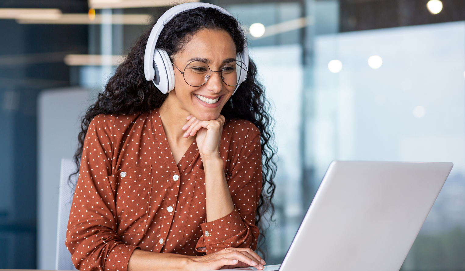 a woman wearing headphones participates in virtual training on a laptop