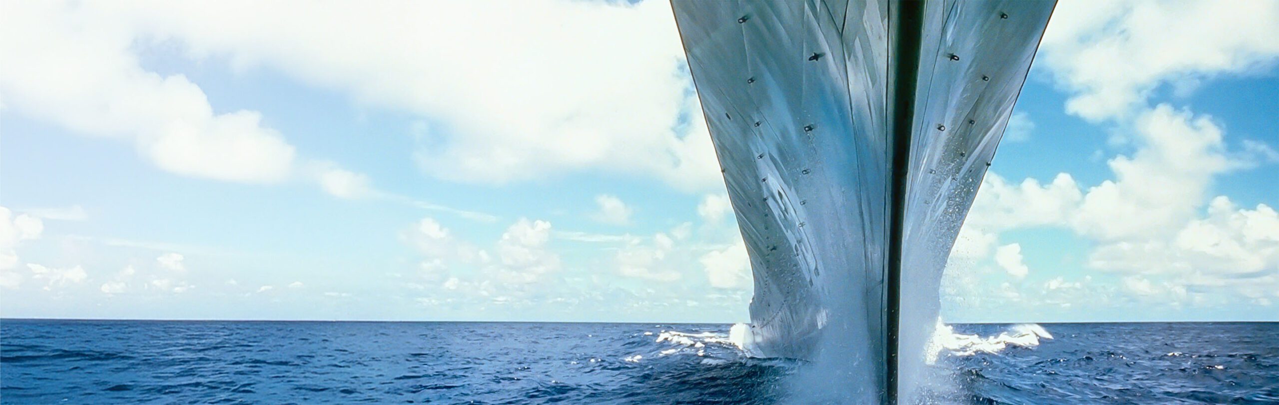 extreme close up on the hull of a ship as it moves towards the viewer in the water leaving waves behind