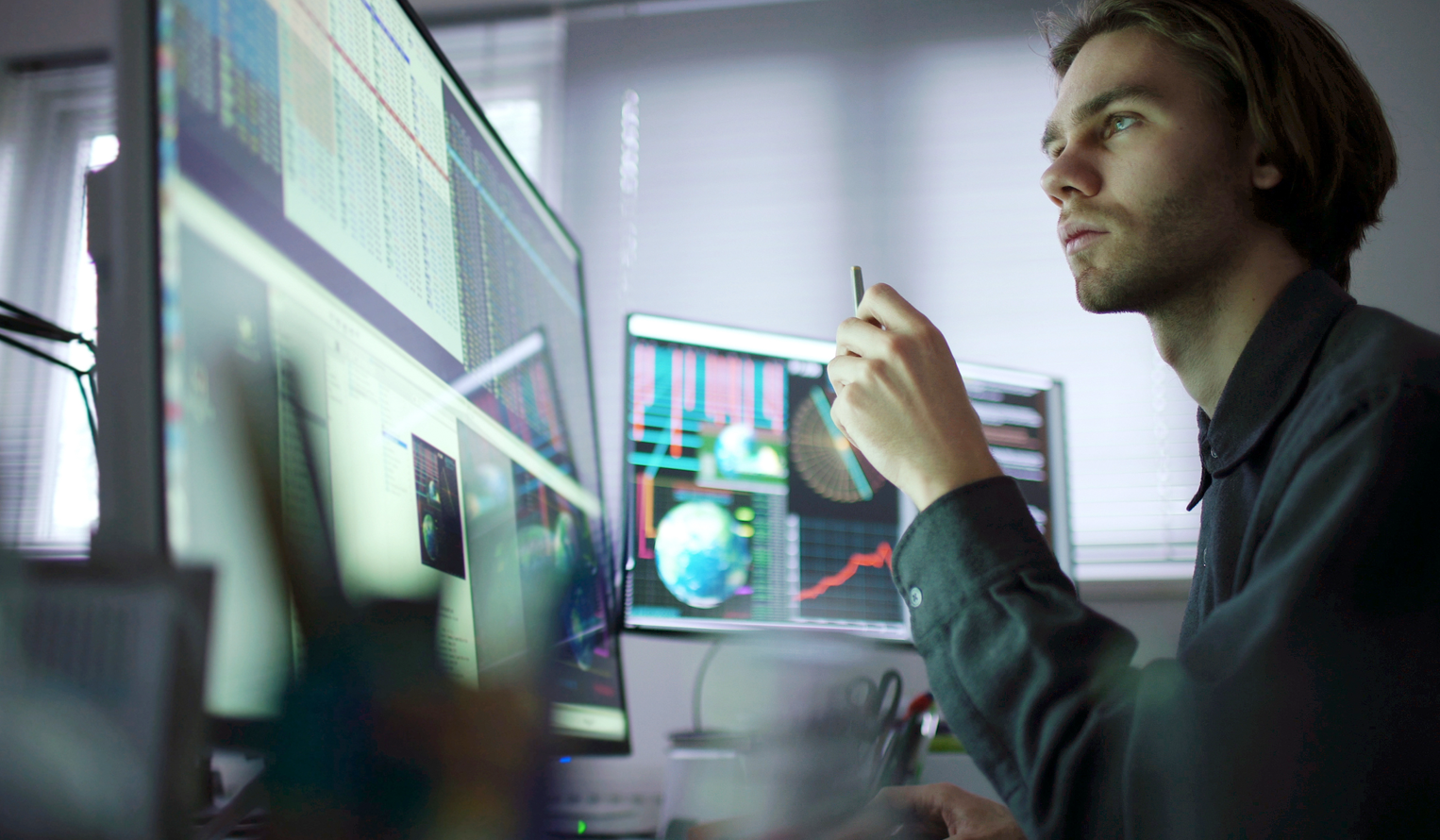 a young man looks at a large computer screen