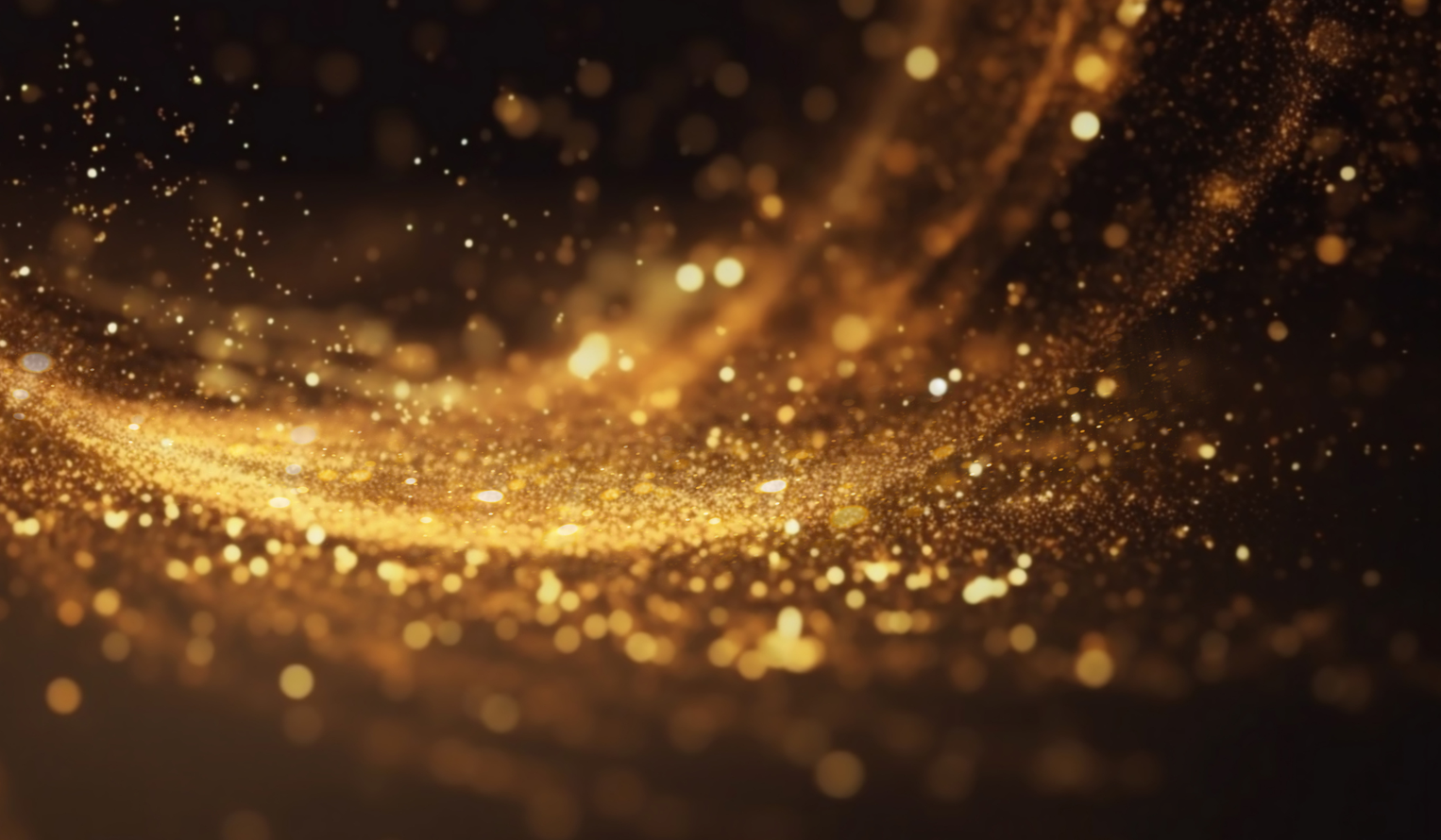 Golden glitter and sparks glowing on a dark background