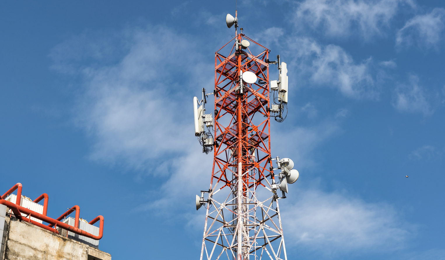 a 4G and 5G mobile communications tower against a blue sky