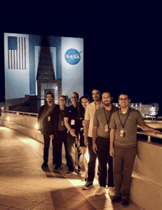 The Noblis Team stands in front of a NASA facility in Ft. Lauderdale, Florida as they wait for the launch of a SpaceX rocket carrying our research projects.