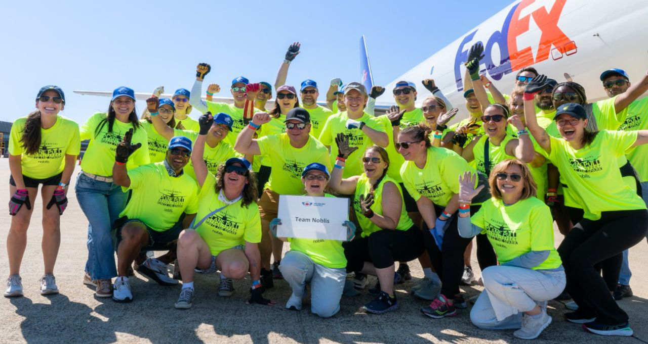 A large group of employees and their family members post in front of the plane.