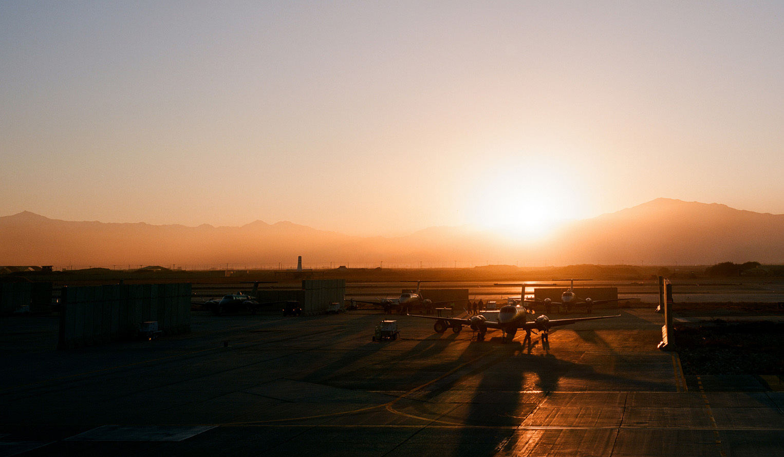 Plane on an airforce base tarmac at sunset with mountains in the distance